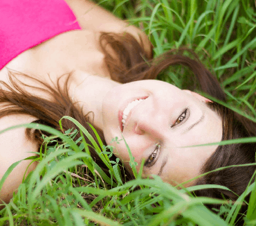 Healthy happy smile of a woman laying in the grass after tooth abscess drainage treatment